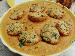 Stuffed potato with curd and cheese, in a tomato gravy.